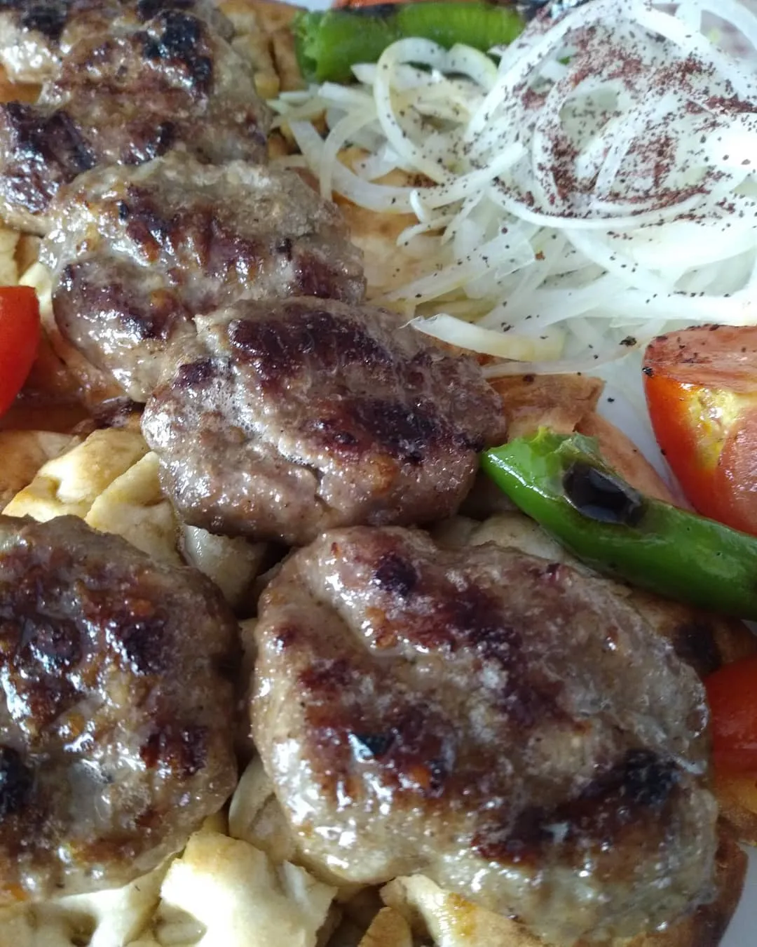 Lavaş üstünde ızgara köfte, sumaklı soğan ve köz biber