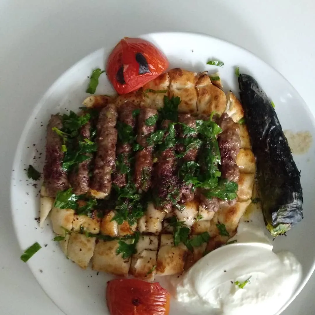 Pide üstünde Manisa kebabı, yoğurt, köz biber ve domates